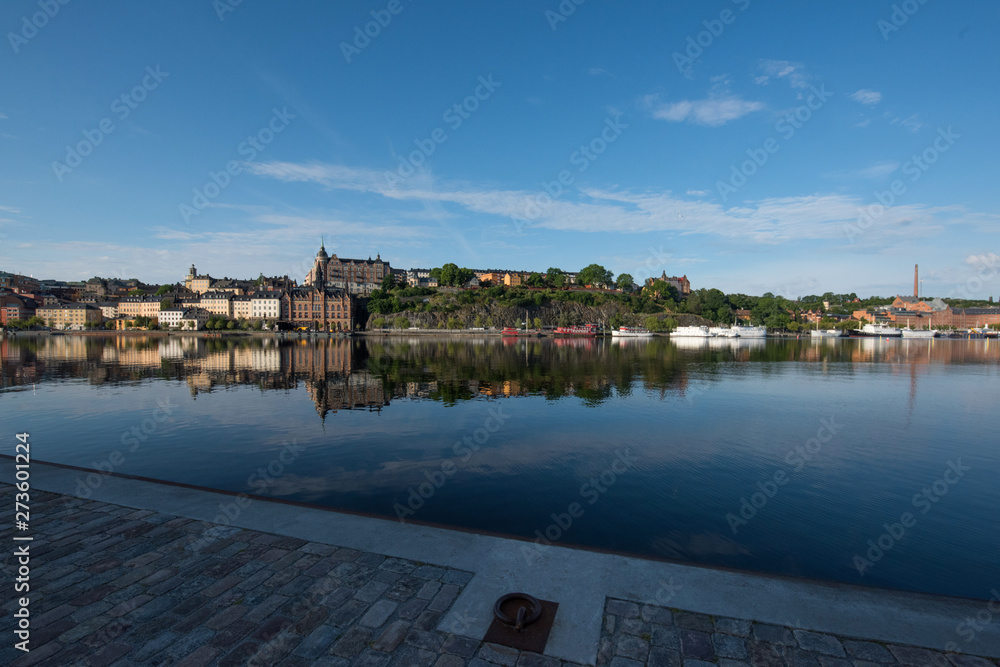 Fototapeta premium Boats, pier and landmarks in Stockholm a tranquil morning, 