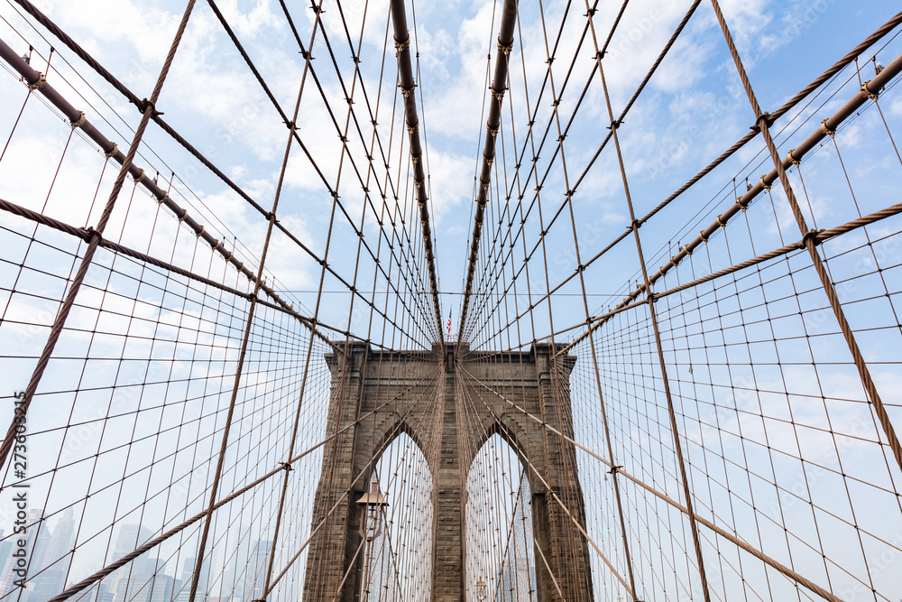Fototapeta premium Brooklyn Bridge detail against blue cloudy sky background. New York city, Manhattan