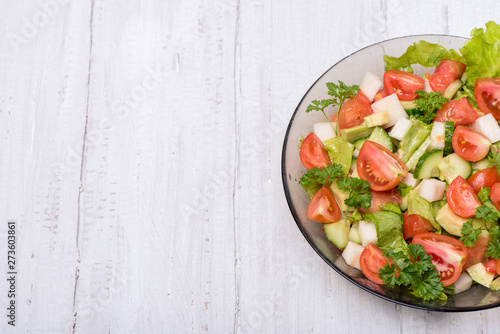 Delicious salad of vegetables, turnips, cucumber, tomato, avocado and parsley on a white background