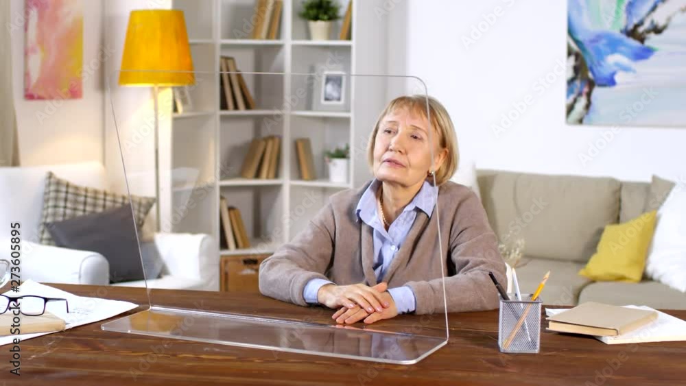 Lockdown of Caucasian aged woman sitting at table and tapping on transparent AR screen of computer Lockdown of Caucasian aged woman sitting at table and tapping on transparent AR screen of computer