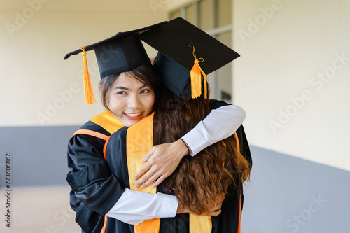 Female university graduates celebrate happily after completed and received diploma degree. The female graduates express congratulations with each other.