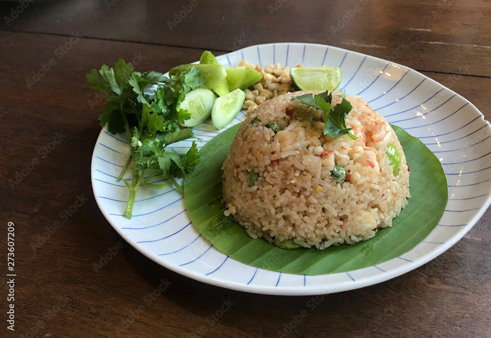 Spicy Chili paste fried rice with fresh shrimp and smelly bean Thai style serving with fresh vegetable on Banaba leaves