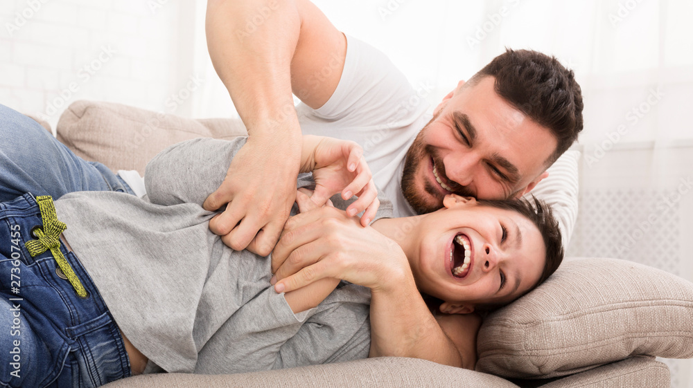 Young dad have fun tickling his laughing son Young dad have fun tickling his laughing son