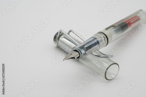 Clear transparent calligraphic or fountain pen on white background with depth of field.