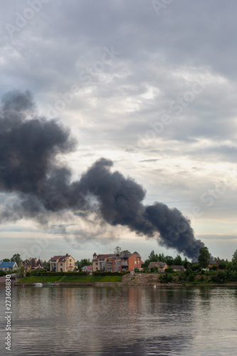 a dangerous cloud of black smoke from a burning house against the background of the evening sky as a background