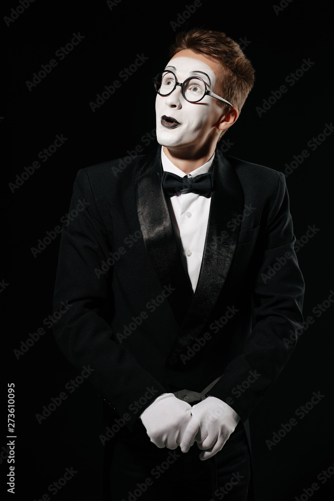 surprised mime man in tuxedo and glasses posing with walking stick on black background