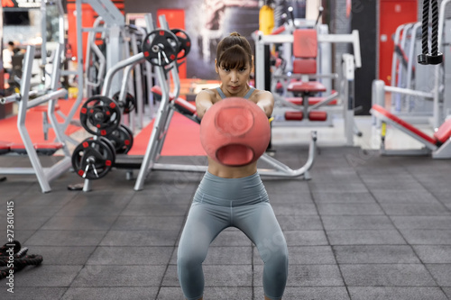 Young beautiful woman asian doing exercises with kettlebell at gym. Fitness and healthy lifestyle concept