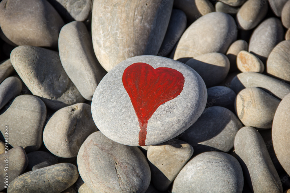 stone heart painted with a red paint marker on the pebble as a gift for Saint Valentine day on the pebble background. stone heart painted with a red paint marker on the pebble as a gift for Saint Valentine day on the pebble background.