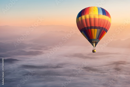 Colorful hot air balloon flying in the air with fog and scenery mountains