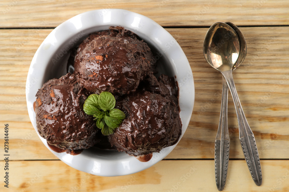 Chocolate ice cream with liquid chocolate and cinnamon sticks on a light concrete background. Chocolate ice cream with liquid chocolate and cinnamon sticks on a light concrete background.