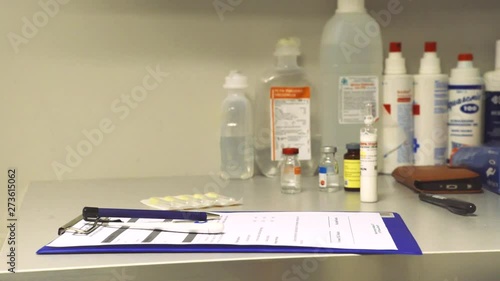 Still medium shot of person taking stethoscope and medical notebook from the table. Bottles with medicie are standing in the background. photo