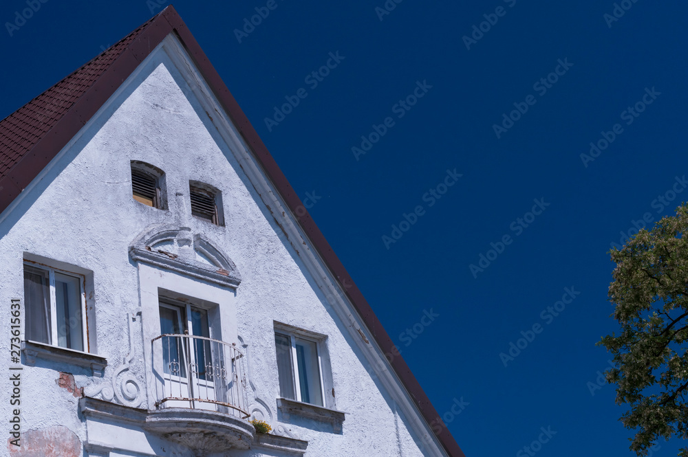 The facade of the attic of the old house against the blue sky