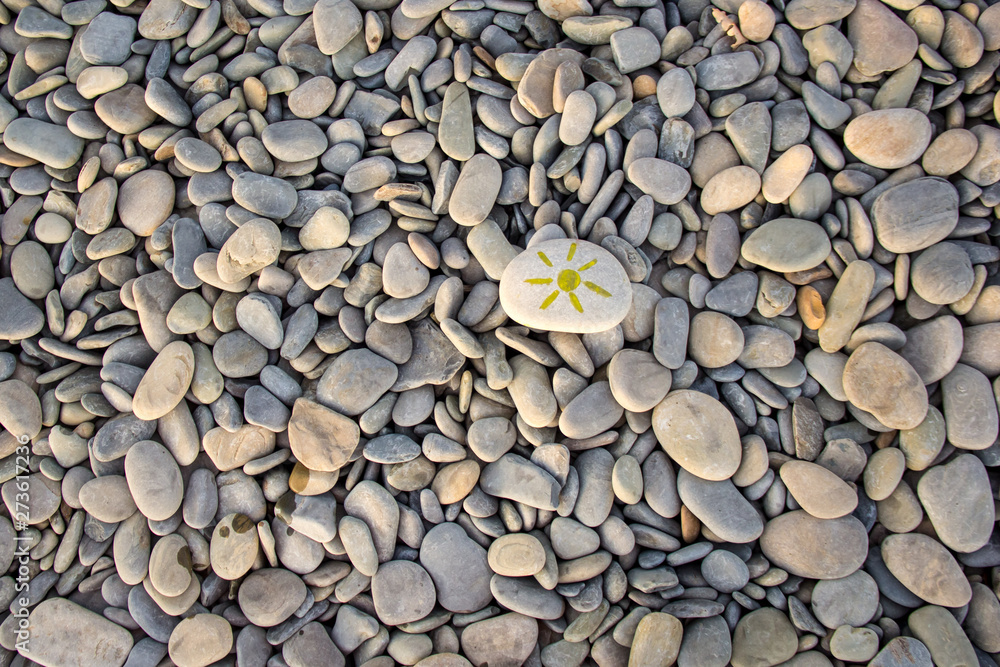 Naklejka premium Bright sun painted on pebble. Pebbles background.