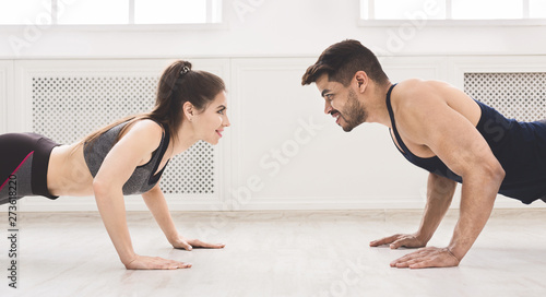 Sporty couple standing in plank in front of each other © Prostock-studio