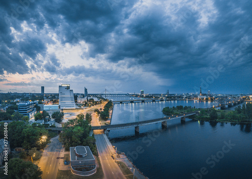 Panoramic view over Riga city covered in storm clouds. Iconic railroad bridge and old town panorama. Picturesque scenery of historical architecture. National library of Latvia. 