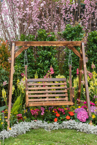 фотографія Wooden swing seat in backyard flower garden