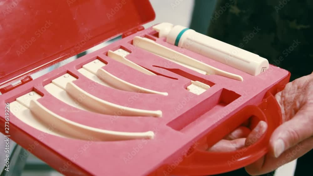 Doctor reveals Laryngoscopy In a red Box with handles. Laryngoscopy is