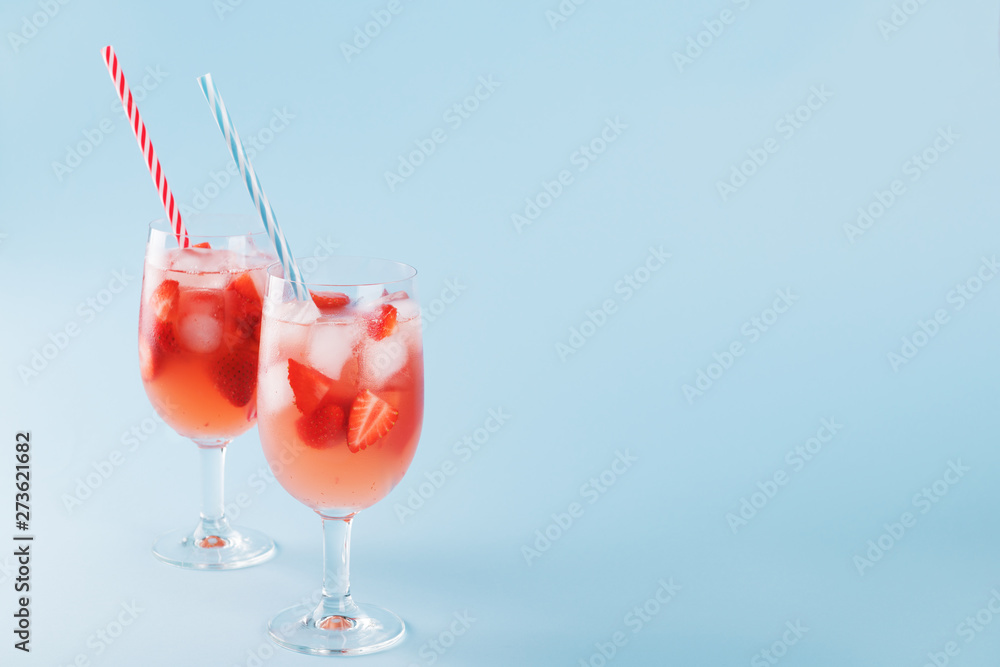 Fresh strawberry summer cocktail and ice cubes. Two glasses with strawberry, ice and wine - strawberry sangria on a pastel blue backgound, minimalism Fresh strawberry summer cocktail and ice cubes. Two glasses with strawberry, ice and wine - strawberry sangria on a pastel blue backgound, minimalism