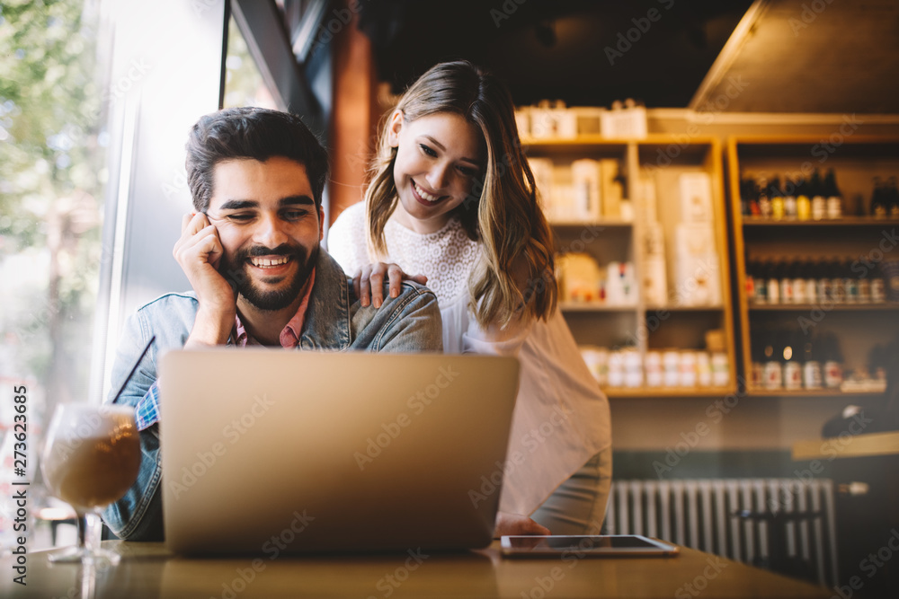 Couple have fun while looking on laptop at cafe Couple have fun while looking on laptop at cafe