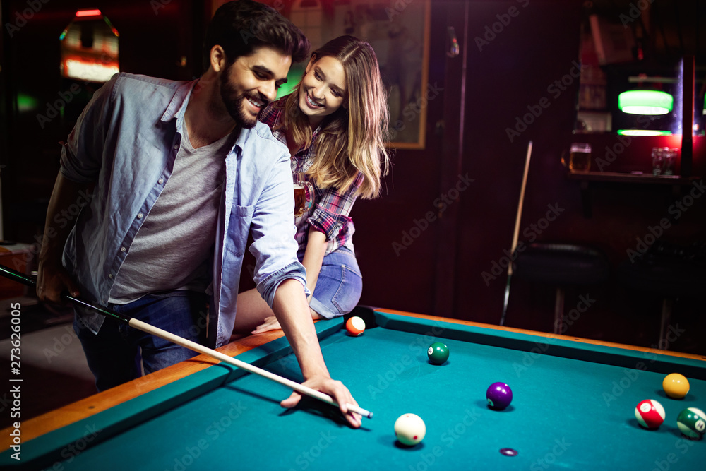 Fototapeta premium Happy young man playing snooker with his girlfriend. Happy loving couple.