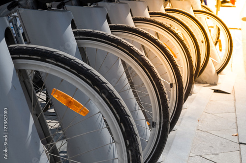 Wheels of parked bikes in the bike rental Parking lot.Bike hire pick up station.Rent a bike cheaply.Bicycle wheel in the perspective of the shot.Parking with bicycles.Sustainable urban transport photo