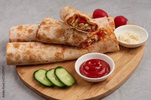 Shawarma, fresh roll of pita, chicken, vegetables. Traditional Middle Eastern snack on a wooden board