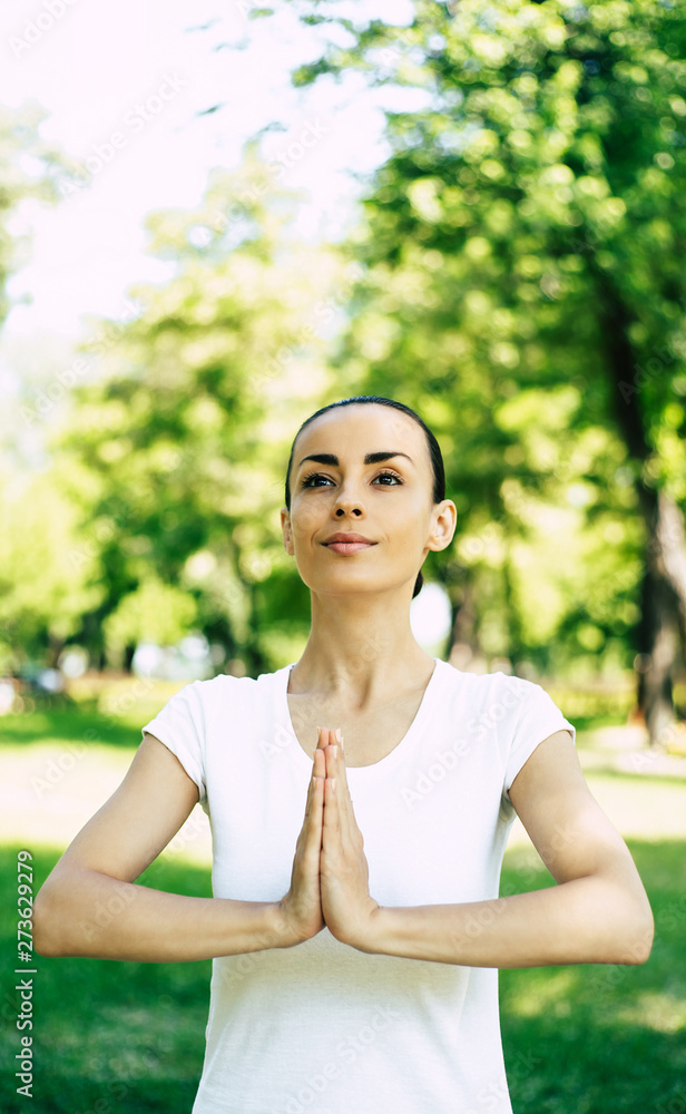 Beautiful young woman doing yoga in park. Relaxing and meditating while being surrounded by nature in summer park Beautiful young woman doing yoga in park. Relaxing and meditating while being surrounded by nature in summer park