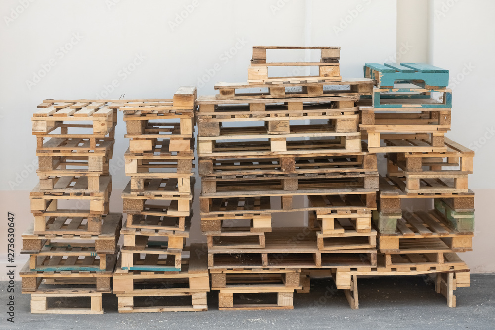 Pallets stacked on top of each other on the ground and against a white wall Pallets stacked on top of each other on the ground and against a white wall