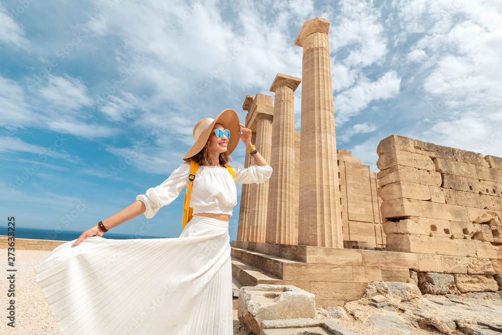 Naklejka premium Happy asian Traveler with backpack walking in historical and archaeological site in Lindos Acropolis. Tourist attraction and ancient architecture in Greece