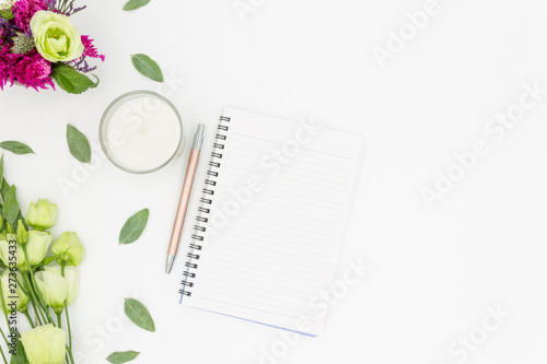 Note pad flat lay with flowers pen and candle white background space for text