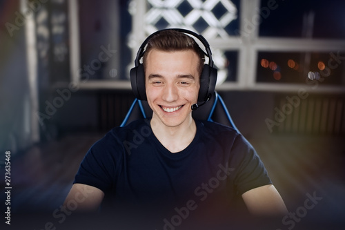 Portrait of ecstatic and smilling gamer guy in headphones while playing online video games on computer                               