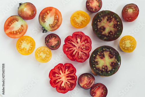 various tomatoes cut on white
