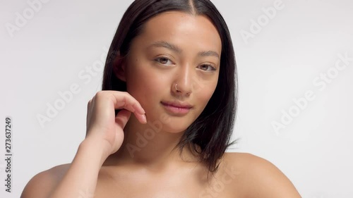 mixed race asian model in studio beauty shoot Model watching aside and then to the camera. Brown eyed model with ideal skin and natural makeup