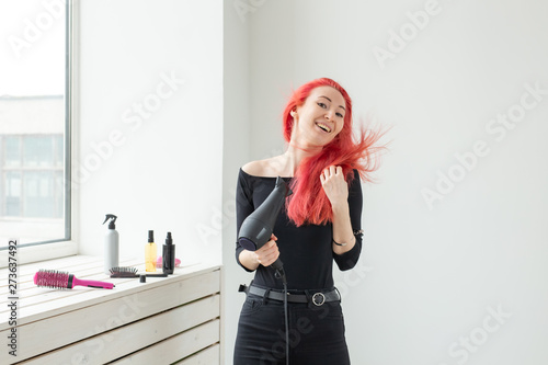 Hairdresser  beauty salon and people concept - young woman hair stylist with hair dryer on white background