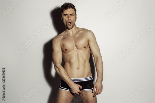 Strong stripped muscle male model in black underwear with white strips on white isolated font background with shadow