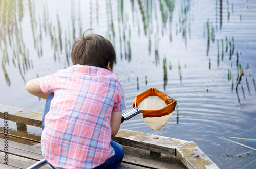 Reaw view Kid boy catching creatures in pond with net in summer time, Selective focus of Child explorer and learning about wild nature in countryside, Summer camp outdoors activity for children photo