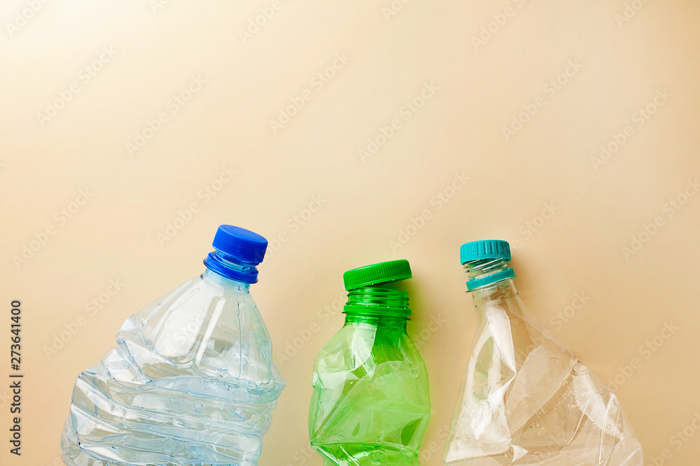 Used empty plastic water bottles crumpled for sorting (segregating) and recycling on coral pink background top view with copy space.Environment pollution.Plastic free.Recycle household waste concept Used empty plastic water bottles crumpled for sorting (segregating) and recycling on coral pink background top view with copy space.Environment pollution.Plastic free.Recycle household waste concept