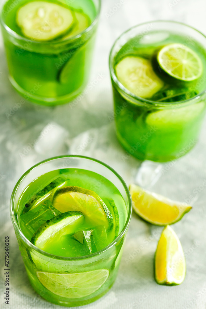 Homemade trendy iced matcha green tea or lemonade with cucumber and lime in a glass on light gray background top view.Healthy cold vegan beverage for hot summer day.Super food drink Homemade trendy iced matcha green tea or lemonade with cucumber and lime in a glass on light gray background top view.Healthy cold vegan beverage for hot summer day.Super food drink