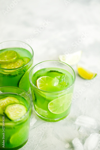 Homemade trendy iced matcha green tea or lemonade with cucumber and lime in a glass on light gray background top view.Healthy cold vegan beverage for hot summer day.Super food drink