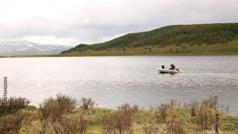 motor boat floats on a mountain lake, hiking and fishing in the mountains motor boat floats on a mountain lake, hiking and fishing in the mountains