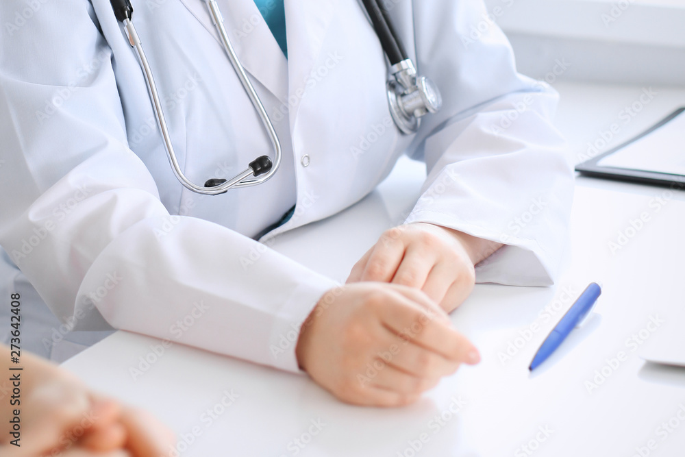 Doctor and patient discussing something while sitting at the desk at hospital, close-up. Medicine and health care Doctor and patient discussing something while sitting at the desk at hospital, close-up. Medicine and health care