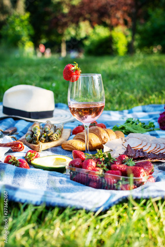 Summer picnic in the park on the grass. Wine, fruit and croissants