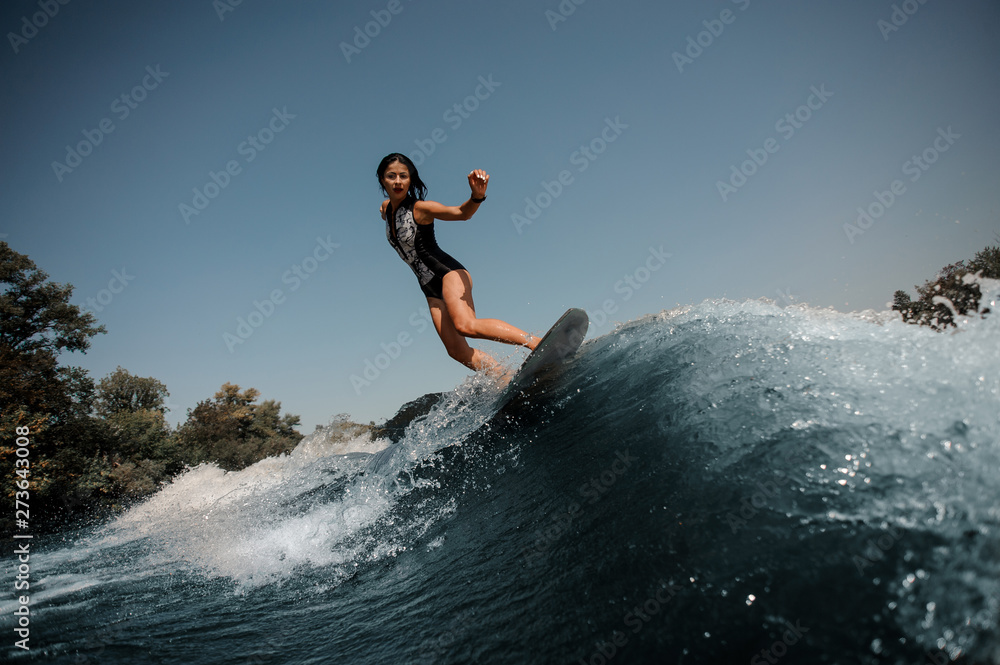 Brunette woman surfing on a surfboard in sea