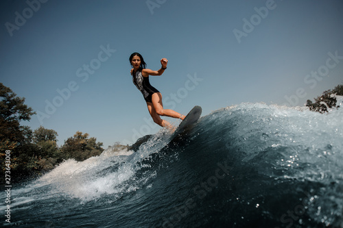 Photography Brunette woman surfing on a surfboard in sea