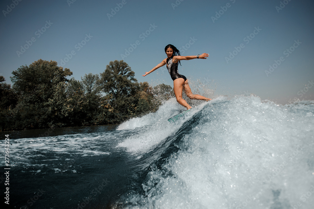 Brunette woman surfs on a surfboard in sea