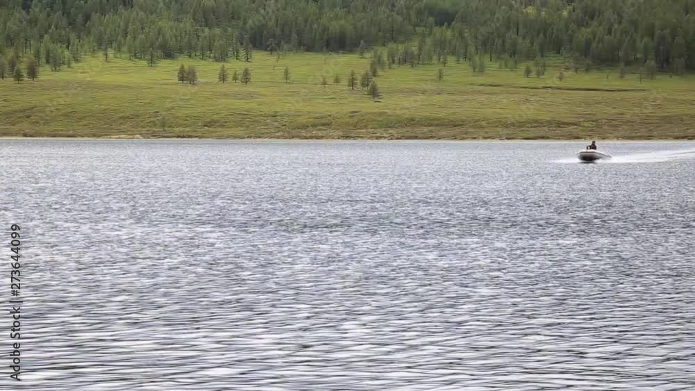 motor boat floats on a mountain lake, hiking and fishing in the mountains motor boat floats on a mountain lake, hiking and fishing in the mountains