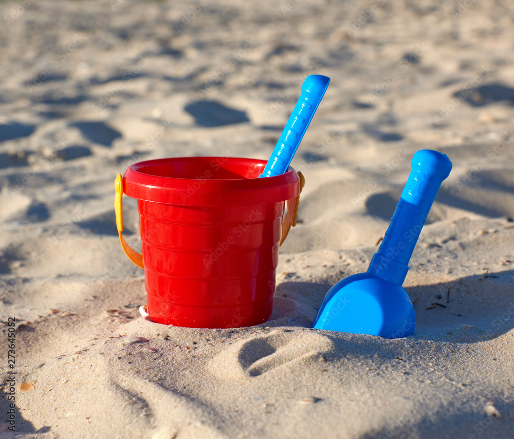 red plastic bucket and blue rake, shovel on the sand red plastic bucket and blue rake, shovel on the sand