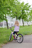 Beautiful blonde young girl riding a white bicycle