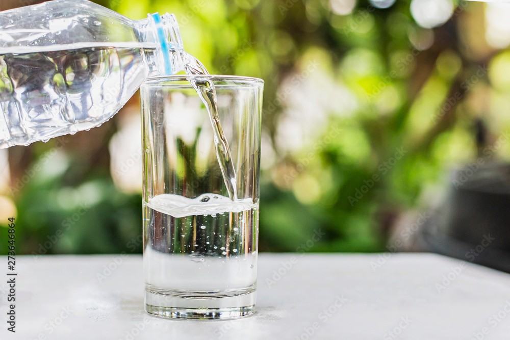 Pouring water from bottle in to glass on bokhe nature background Pouring water from bottle in to glass on bokhe nature background