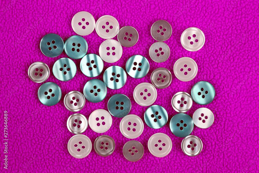Fototapeta premium different mother of pearl buttons on a pink cloth.